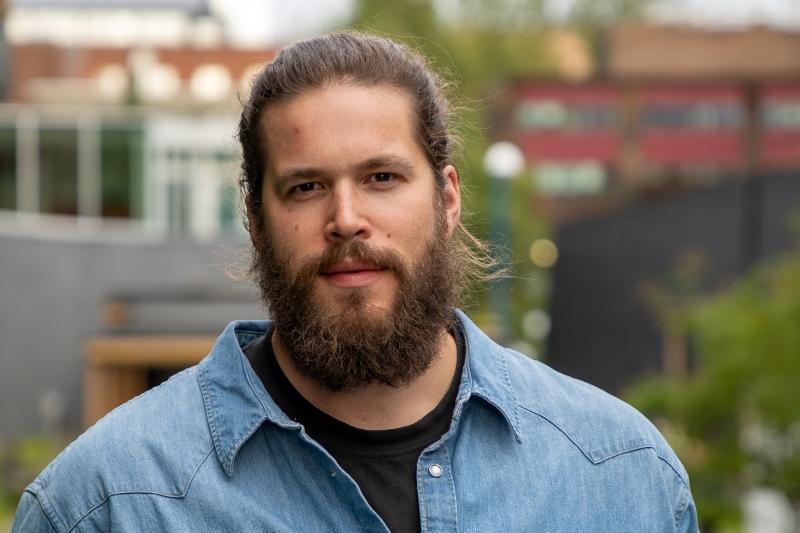 troy saghaug broderstad-230906.jpg Portrett av ein mann, utandørs. Han har langt hår i hestehale og eit stort skjegg.